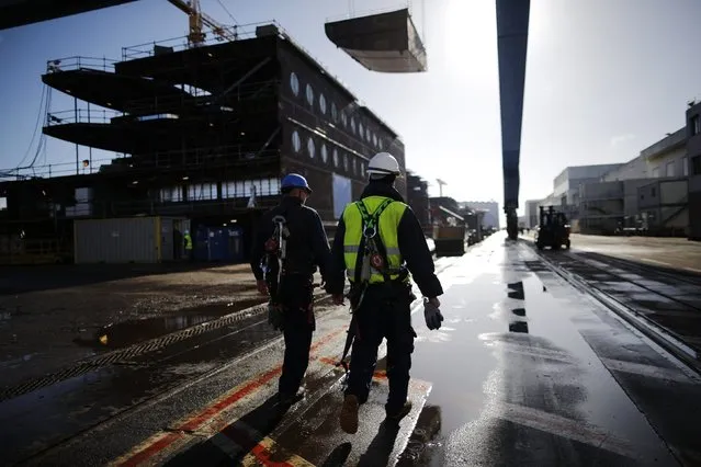 Ship builders walk past a section of the Oasis Class 3 cruise ship under construction at the STX Les Chantiers de l'Atlantique shipyard site in Saint-Nazaire, western France, February 17, 2015. (Photo by Stephane Mahe/Reuters)