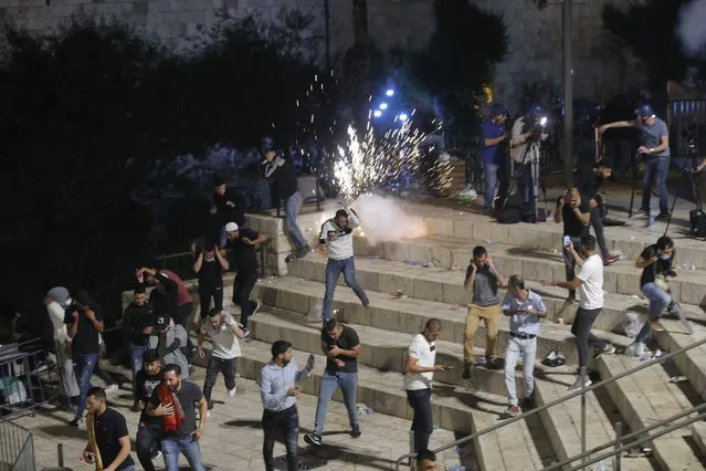 Palestinians run from stun grenades fired by Israeli police officers during clashes at Damascus Gate just outside Jerusalem's Old City, Saturday, May 8, 2021. Israeli police on Saturday clashed with Palestinian protesters outside Jerusalem's Old City during the holiest night of Ramadan, in a show of force that threatened to deepen the holy city's worst religious unrest in several years. (Photo by Oded Balilty/AP Photo)