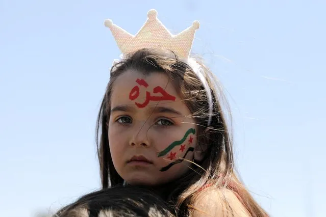 A girl, with her face painted with the colours of the opposition flag, looks on during a demonstration against Syria's President Bashar al-Assad and presidential elections, in the opposition-held Idlib, Syria on May 26, 2021. (Photo by Khalil Ashawi/Reuters)
