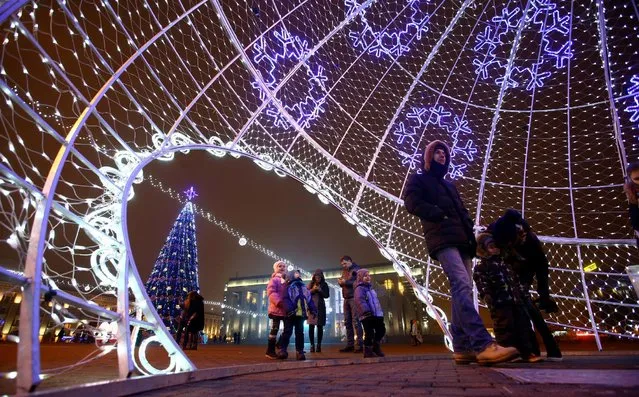 People walk into a giant illuminated Christmas ball installed on Oktyabrskaya Square for the upcoming New Year and Christmas season in Minsk, Belarus December 21, 2016. (Photo by Vasily Fedosenko/Reuters)