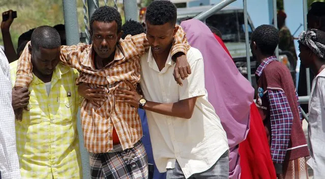 Somalis help a civilian who was wounded in suicide bomb attack at a military base in Mogadishu, Somalia, Tuesday, June 15, 2021. Police in Somalia say at least 15 people were killed and more than 20 others wounded when a suicide bomber attacked a military training center in the capital, Mogadishu, on Tuesday. (Photo by Farah Abdi Warsameh/AP Photo)