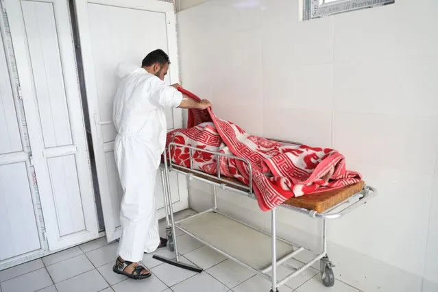 An Afghan health worker checks the body of a woman who died from COVID-19 at the Afghan-Japan Communicable Disease Hospital in Kabul, Afghanistan, Sunday, May 30, 2021. Afghanistan is battling a brutal third wave of COVID infections, while health officials plead for vaccines, expressing deep frustration at the inequities of the global vaccine distribution. Positive COVID cases jump from eight percent to 60 per cent in some parts of the country. (Photo by Rahmat Gul/AP Photo)