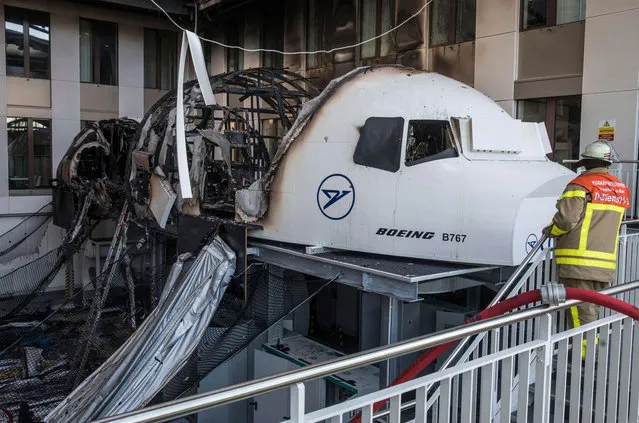 A firefighter stands in the office of Condor airlines next to a burned out flight simulator in the airport in Frankfurt am Main, Germany, Thursday December 29, 2016. The flight simulator has caught fire in an office block at Frankfurt airport, forcing some 200 people to leave the building. The fire service says one person was taken to a hospital suffering from the effects of smoke inhalation. (Photo by Frank Rumpenhorst/dpa via AP Photo)