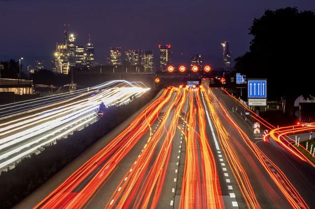 Cars and trucks move on a highway near Frankfurt, Germany, early Tuesday, October 17, 2023. In background the buildings of the banking district. (Photo by Michael Probst/AP Photo)