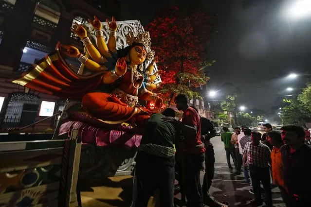 Laborers unload a clay idol of Hindu goddess Durga from a truck to place at a worship site ahead of Durga Puja festival in Kolkata, India, September 27, 2022. The five-day festival commemorates the slaying of a demon king by goddess Durga, marking the triumph of good over evil. (Photo by Bikas Das/AP Photo)