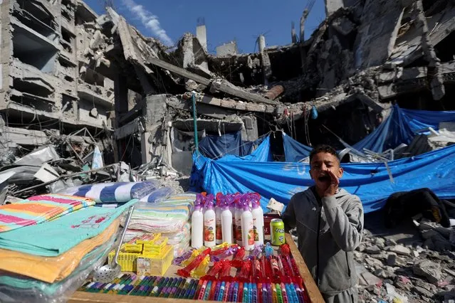 A Palestinian vendor offers his products in an open-air market near the ruins of houses and buildings destroyed in Israeli strikes during the conflict, amid a temporary truce between Hamas and Israel, in Nuseirat refugee camp in the central Gaza Strip on November 30, 2023. (Photo by Ibraheem Abu Mustafa/Reuters)