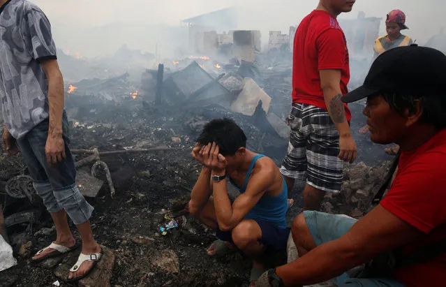 Victims wait for the ruins of their homes to cool down so that they can recover recyclable materials after a fire at a squatter colony in Navotas, Metro Manila in the Philippines January 10, 2017. (Photo by Erik De Castro/Reuters)