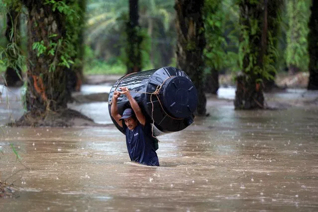 A man carries an empty water tank through a flooded area after the impact of the tropical storm Julia, in Progreso, Honduras on October 9, 2022. (Photo by Yoseph Amaya/Reuters)