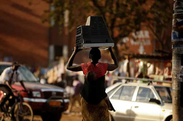 A woman carries a television set on her head and a baby on her back at Mbare township outside the capital Harare, Zimbabwe, July 31, 2018. (Photo by Siphiwe Sibeko/Reuters)