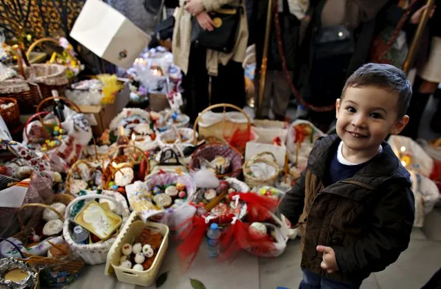 Imran, a 3-year old boy from the Ukrainian Orthodox community living in Turkey, stands next to baskets of “paskha” cakes and eggs during the Easter service at the Orthodox Patriarchal Cathedral of St. George in Istanbul, April 12, 2015. (Photo by Murad Sezer/Reuters)