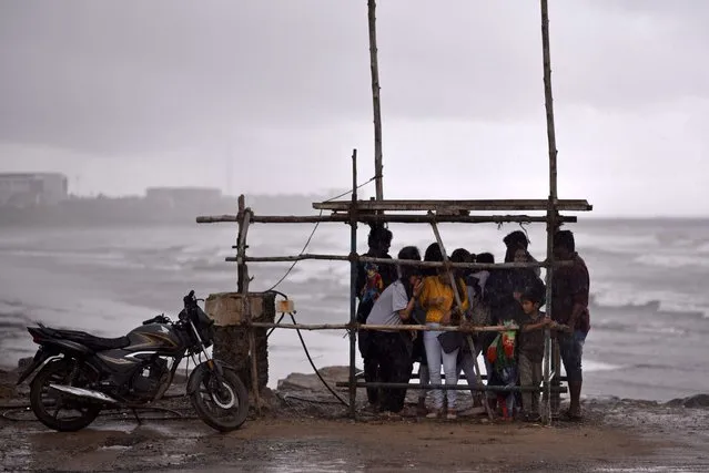 People gather as they take cover under a makeshift shelter from heavy rain during Cyclone Michaung, at Kasimedu Beach, in Chennai, India, 02 December 2023. The Indian Meteorological Department has issued an orange alert for heavy to very heavy rains in Tamil Nadu, Puducherry, and Karaikal for the next 48 hours as a deep depression over the Bay of Bengal is to intensify into a cyclonic storm, “Cyclone Michaung” during the next 24 hours. It is anticipated to make landfall along the coastlines of Andhra Pradesh and Tamil Nadu around December 04 or December 05. (Photo by Idrees Mohammed/EPA)
