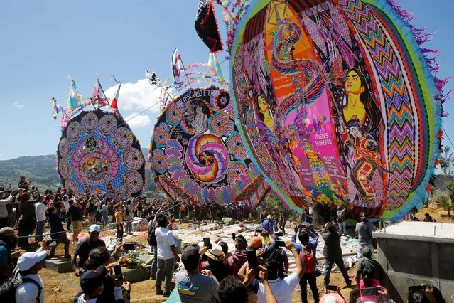 Residents lift a giant kite during the celebration of All Saints Day, in Santiago Sacatepequez, Guatemala on November 1, 2022. (Photo by Luis Echeverria/Reuters)