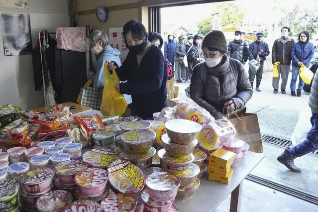 People affected by a strong earthquake receive food in Wajima, Ishikawa prefecture, Japan Friday, January 5, 2024. Monday’s temblor decimated houses, twisted and scarred roads and scattered boats like toys in the waters, and prompted tsunami warnings. (Photo by Kyodo News via AP Photo)