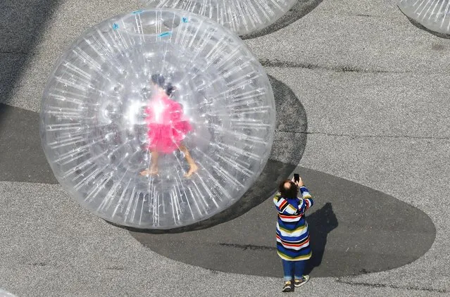 An artist is seen in a transparent plastic ball during the performance “Tears” by Monster Chetwynd in front of the venue of the Art Basel art fair at the Messeplatz square in Basel, Switzerland on September 21, 2021. (Photo by Arnd Wiegmann/Reuters)