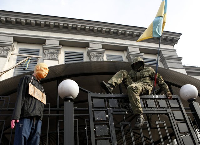 An activist in uniform climbs over the fence to the territory of the Russian embassy in Kiev, Ukraine, Sunday, March 6, 2016. About 2,000 people rallied on Independence Square in Kiev on Sunday to demand that Russia release Ukrainian pilot Nadezhda Savchenko, with hundreds then marching to the Russian Embassy to vent their anger. Savchenko was captured in June 2014 while fighting with a Ukrainian volunteer battalion against Russia-backed rebels in eastern Ukraine. (Photo by Sergei Chuzavkov/AP Photo)