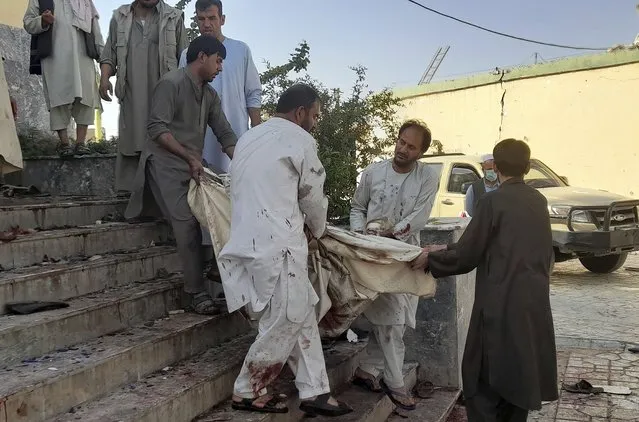 People carry the body of a victim from a mosque following a bombing in Kunduz province, northern Afghanistan, Friday, October 8, 2021. A powerful explosion in a mosque frequented by a Muslim religious minority in northern Afghanistan on Friday has left several casualties, witnesses and the Taliban's spokesman said. (Photo by Abdullah Sahil/AP Photo)