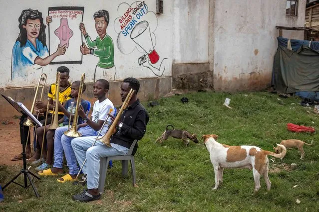 Members of a community brass band take a break during a rehearsal ahead of a performance at the Bwaise informal settlement in Kampala on January 23, 2024. Brass for Africa empowers children and young people from disadvantaged backgrounds in Uganda to positively transform their lives using community brass bands and music as tool to drive social impact and develop life skills. (Photo by Luis Tato/AFP Photo)