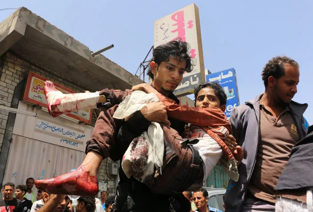 In this Sunday, April 26, 2015 photo, a man carries a boy who was injured during a crossfire between tribal fighters and Shiite militia known as Houthis, in Taiz, Yemen. (Photo by Abdulnasser Alseddik/AP Photo)