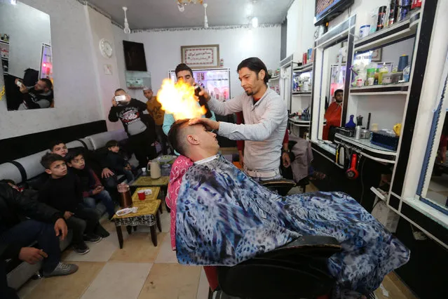 Palestinian barber Ramadan Odwan styles and straightens the hair of a customer with fire at his salon in Rafah, in the southern Gaza Strip February 2, 2017. (Photo by Ibraheem Abu Mustafa/Reuters)