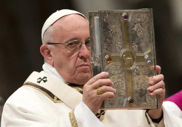 Pope Francis holds the Gospel book as he leads a Chrism Mass in St. Peter's Basilica at the Vatican Thursday, March 24, 2016. During the Mass the Pontiff blesses a token amount of oil that will be used to administer the sacraments for the year. (Photo by Alessandra Tarantino/AP Photo)