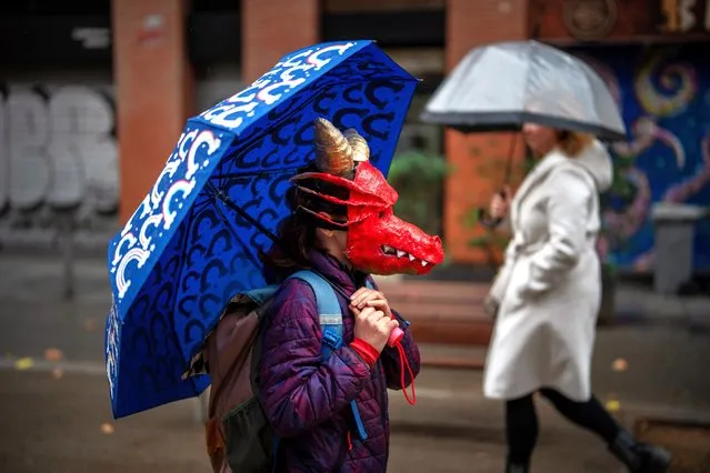 A girl wearing a dragon mask walks towards the school where a costume party awaits her during a carnival celebration in Barcelona, Spain, Friday, February 9, 2024. (Photo by Emilio Morenatti/AP Photo)