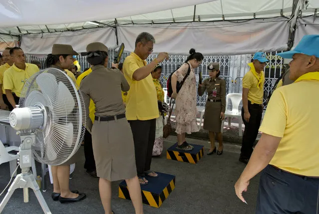 Police officers use metal detectors to check people who arrive to watch King Maha Vajiralongkorn's coronation ceremony Sunday, May 5, 2019, in Bangkok, Thailand. Saturday began three days of elaborate centuries-old ceremonies for the formal coronation of Vajiralongkorn, who has been on the throne for more than two years following the death of his father, King Bhumibol Adulyadej, who died in October 2016 after seven decades on the throne. (Photo by Gemunu Amarasinghe/AP Photo)