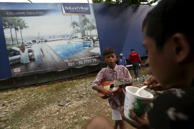 A child street singer practices a song in front of a billboard advertising luxury apartments in Jakarta, Indonesia, March 31, 2016. (Photo by Reuters/Beawiharta)