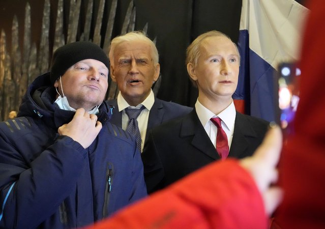 A man poses for photo next to wax figures depicting U.S. President Joe Biden and Russian President Vladimir Putin displayed at a wax sculptures exhibition in St. Petersburg, Russia, Monday, December 6, 2021. President Joe Biden and Russian President Vladimir Putin will speak in a video call Tuesday as tensions between the U.S. and Russia escalate over a Russian troop buildup on the Ukrainian border seen as a sign of a potential invasion. (Photo by Dmitri Lovetsky/AP Photo)