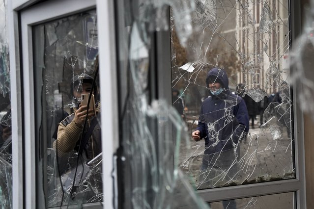 A man takes a photo of windows of a police kiosk damaged by demonstrators during a protest in Almaty, Kazakhstan, Wednesday, January 5, 2022. (Photo by Vladimir Tretyakov/AP Photo)