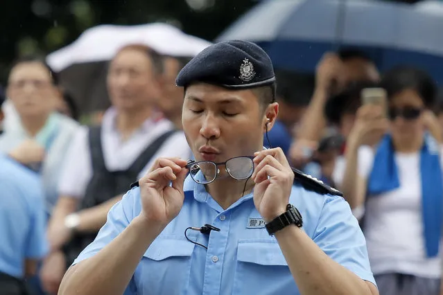A police officer tries to clean his glasses during a rally outside Legislative Council Complex in Hong Kong, Sunday, June 30, 2019. Pro-China's supporters rallied in support of the police at Tamar Park (Photo by Kin Cheung/AP Photo)