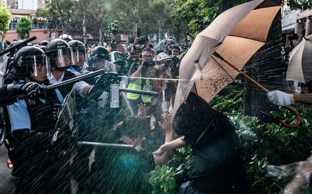 Police officers use pepper spray to disperse protesters after a rally in Sheung Shui district on July 13, 2019 in Hong Kong, China. Protesters in Hong Kong clashed with the police after thousands rallied in Sheung Shui against mainland Chinese parallel traders on Sunday while pro-democracy demonstrators continued weekly rallies on the streets of Hong Kong for the past month, calling for the complete withdrawal of a controversial extradition bill. Hong Kong's Chief Executive Carrie Lam has suspended the bill indefinitely, however protests have continued with demonstrators now calling for her resignation. (Photo by Anthony Kwan/Getty Images)
