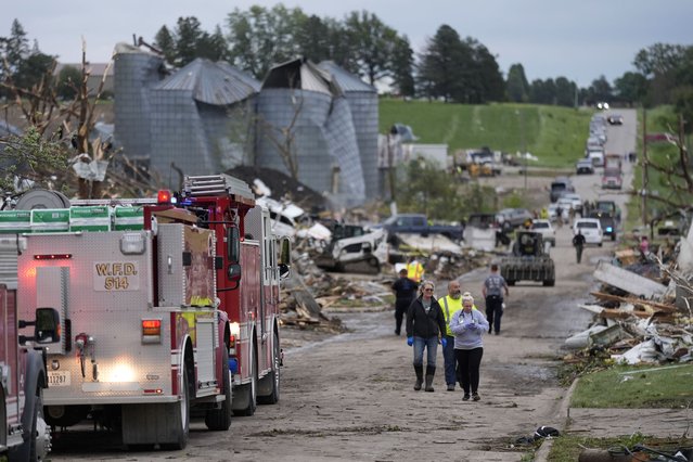 People walk down a street past damage after a tornado Tuesday, May 21, 2024, in Greenfield, Iowa. (Photo by Charlie Neibergall/AP Photo)