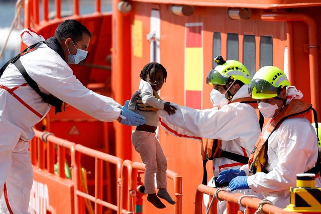 A rescuer helps a migrant child to disembark from a Spanish coast guard vessel at the port of Arguineguin, on the island of Gran Canaria, Spain on May 20, 2024. (Photo by Borja Suarez/Reuters)