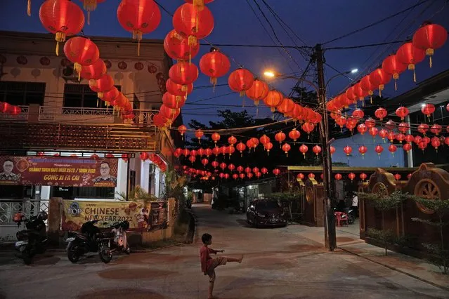 A young boy plays under lanterns decorating Hok Lay Kiong temple on the evening of Chinese New year, in Bekasi, Indonesia, Monday, January 31, 2022. People across Asia prepared Monday for muted Lunar New Year celebrations amid concerns over the coronavirus and virulent omicron variant, even as increasing vaccination rates raised hopes that the Year of the Tiger might bring life back closer to normal. (Photo by Dita Alangkara/AP Photo)