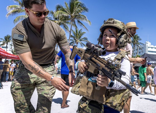 A young person wearing military special forces gear holds a gun in the army village during Memorial Day weekend celebrations in Miami Beach, Florida, USA, 25 May 2024. The two day Hyundai Air & Sea Show event showcases the men, women, technology and equipment from all five branches of the United States Military as well as police, firefighters and first responder agencies. (Photo by Cristobal Herrera/EPA)