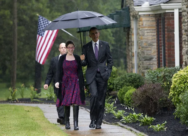 President Barack Obama stops with an umbrella to protect from the rain to pick up Kelly Bryant at her home in Nashville, Tenn., Wednesday, July 1, 2015, en route to Taylor Stratton Elementary School, where he is to speak about the Affordable Care Act. (Photo by Carolyn Kaster/AP Photo)