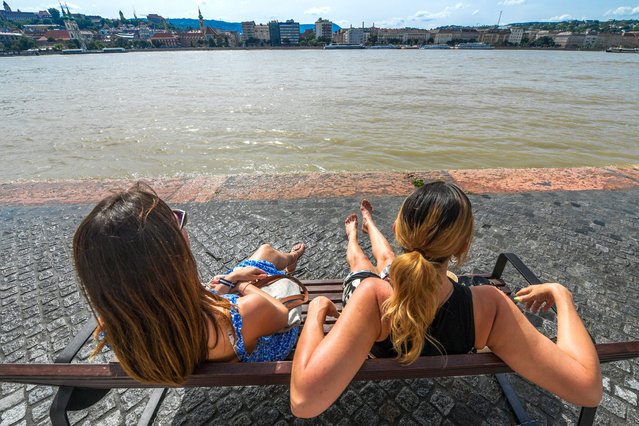 Two women sit on a bench on the bank of the flooded Danube on a sunny day in Budapest, Hungary on June 9, 2024. (Photo by Ferenc Isza/AFP Photo)