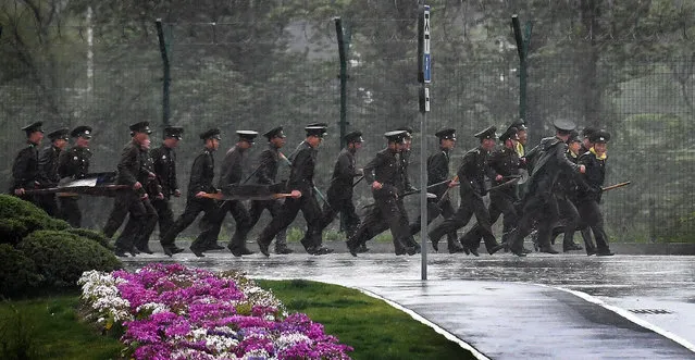 Military personnel run through the pouring rain outside the main airport in Pyongyang, North Korea on May 3, 2016. (Photo by Linda Davidson/The Washington Post)