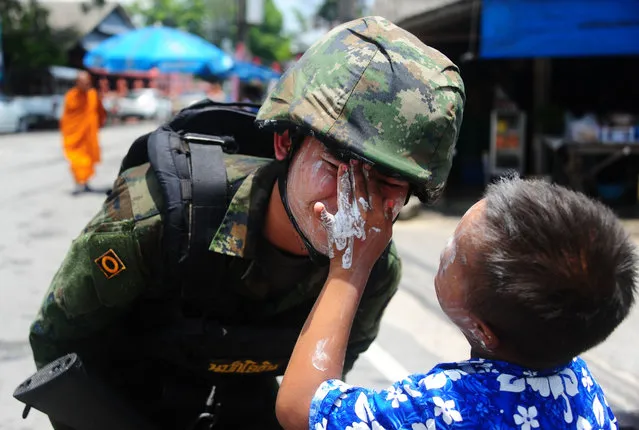 A boy rubs powder on the face of a soldier during Songkran, or Thai New Year, celebrations in the restive southern Thai province of Narathiwat on April 13, 2017. (Photo by Madaree Tohlala/AFP Photo)