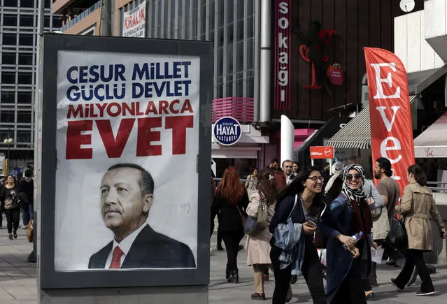 People walk past a “YES” billboard with an image of Turkey's President Recep Tayyip Erdogan's ahead of the Sunday referendum, in Ankara, Turkey, Friday, April 14, 2017. Turkey is heading to a contentious April 16 referendum on constitutional reforms to expand President Recep Tayyip Erdogan's powers. (Photo by Burhan Ozbilici/AP Photo)