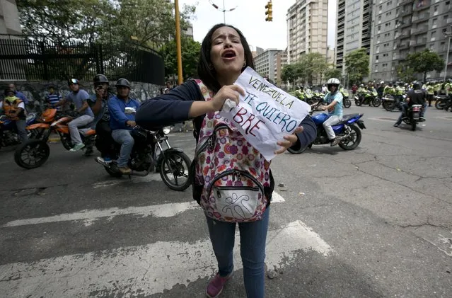 An anti-government demonstrator holds a sign that reads in Spanish: “Venezuela I want you free” during a march toward the headquarters of the national electoral body, CNE, in Caracas, Venezuela, Wednesday, May 18, 2016. Police blocked protesters trying to reach the CNE to demand a referendum to recall Venezuela's President Nicolas Maduro. (Photo by Ariana Cubillos/AP Photo)