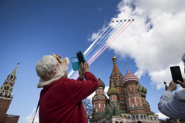 Tourists takes photos of Russian jets flying over the Kremlin during a rehearsal for the Victory Day military parade which will take place on May 9 to celebrate 72 years since the victory of  WWII, in Moscow, Russia, Thursday, May 4, 2017. (Photo by Pavel Golovkin/AP Photo)
