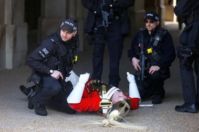 A member of the Household Cavalry lies on the ground after falling from his horse during the Changing of the Guard ceremony in London, Britain on March 28, 2022. (Photo by Tom Nicholson/Reuters)