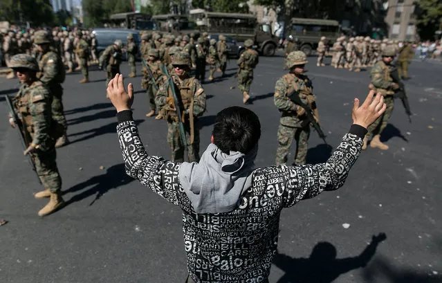 Protester raise their arms in front of th chilean armed soldiers in a peaceful signal during the protest in Santiago, Chile, Monday, October 21, 2019. After President Sebastian Pinera decreed a state of emergency due to the protests that began on Friday due to the rise in the fare of the subway ticket and where high school students mobilized and called to evade this transport in bulk  jumping access turnstiles and vandalizing stations. (Photo by Jose Miguel Rojas/SIPA Press)
