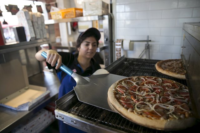 A worker takes a vegan pizza out of the oven at a Domino's Pizza restaurant in Tel Aviv, Israel July 16, 2015. (Photo by Baz Ratner/Reuters)