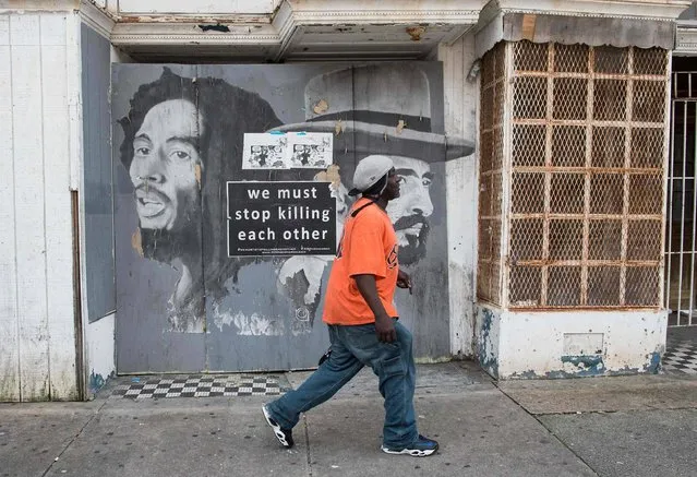 A man walks past a sign reading “We Must Stop Killing Each Other” in the neighborhood where Freddie Gray was arrested last year in Baltimore, Maryland, on May 23, 2016. (Photo by Nicholas Kamm/AFP Photo)