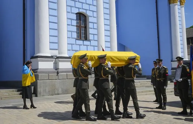 Soldiers carry a coffin with remains of a volunteer soldier Oleksandr Makhov, a well-known Ukrainian journalist, killed by the Russian troops, at St Michael cathedral in Kyiv, Ukraine, Monday, May 9, 2022. The coffin is followed by Makhov's widow. (Photo by Efrem Lukatsky/AP Photo)