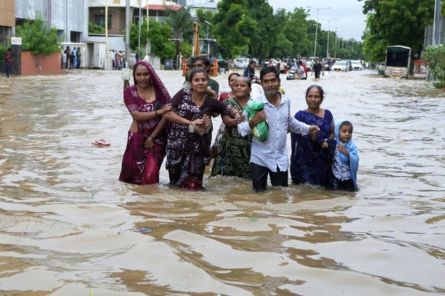 A family wades through a flooded road after heavy rain in Ahmedabad, India, Monday, August 26, 2024. (Photo by Ajit Solanki/AP Photo)