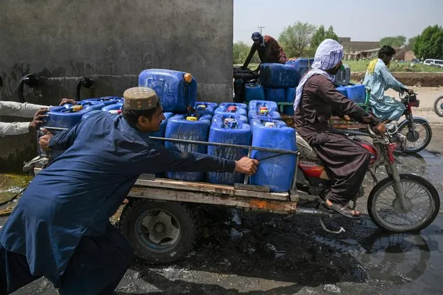 In this picture taken on May 11, 2022, vendors fill cans with drinking water from a water supply plant for selling during heatwave in the Pakistan's hottest city of Jacobabad in southern Sindh province. (Photo by Aamir Qureshi/AFP Photo)