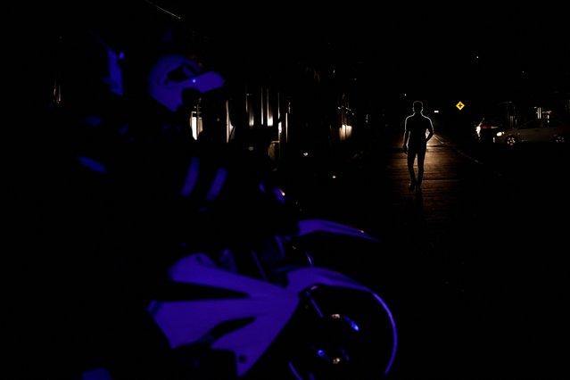 The silhouette of a man as he walks away from a police operation, during a nationwide blackout for maintenance in the country's electricity system overnight on Wednesday, in Puyo, Ecuador on September 18, 2024. (Photo by Karen Toro/Reuters)